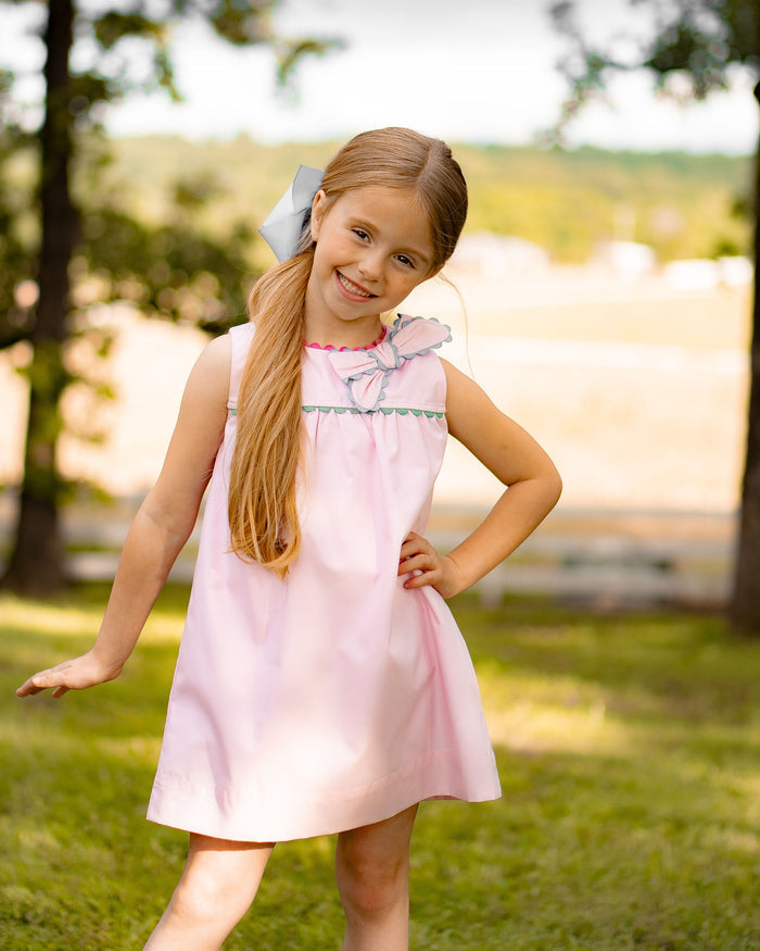 Introducing the Annie Bow Dress from The Yellow Lamb, a must-have for toddler girls. This light pink dress features a beautiful bow on one shoulder with colorful ric rac detail. Dress up your little one in style and complete the look for sisters with the matching pantaloon set for infant girls.