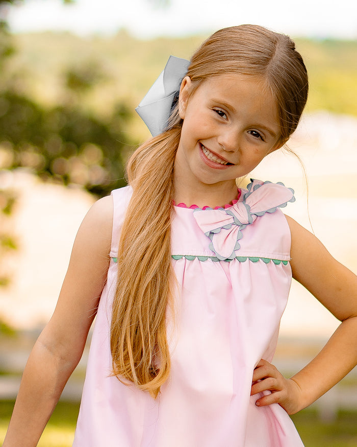Introducing the Annie Bow Dress from The Yellow Lamb, a must-have for toddler girls. This light pink dress features a beautiful bow on one shoulder with colorful ric rac detail. Dress up your little one in style and complete the look for sisters with the matching pantaloon set for infant girls.