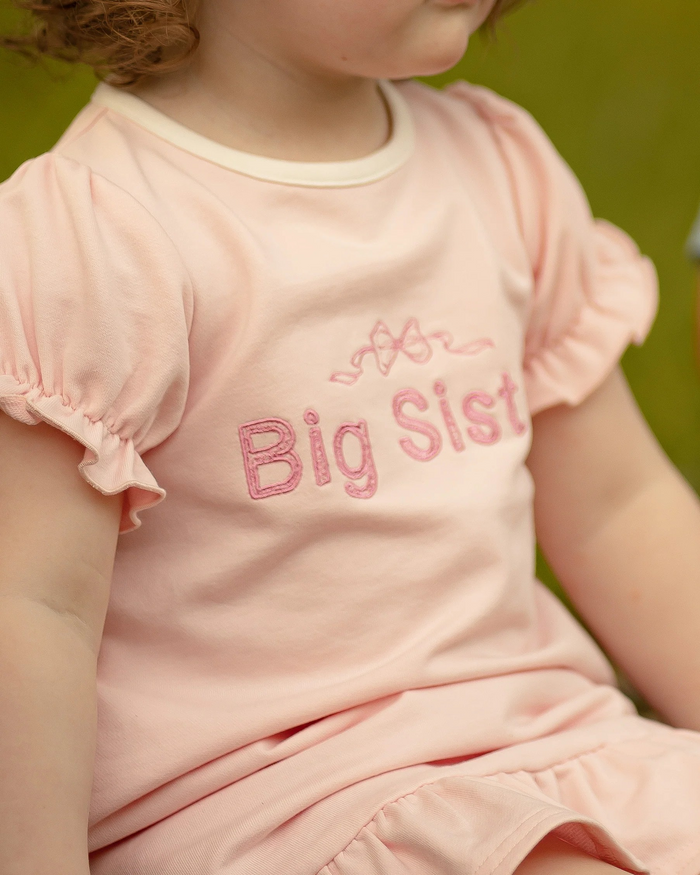A sweet dress for the most precious Big Sister announcement! Ultra comfortable knit fabric with princess sleeves with elastic cuffs, crew neck with single button back closure. Fun ruffled dress hem. Custom bow and big sister embroidery on chest. Polyester spandex blend knit.