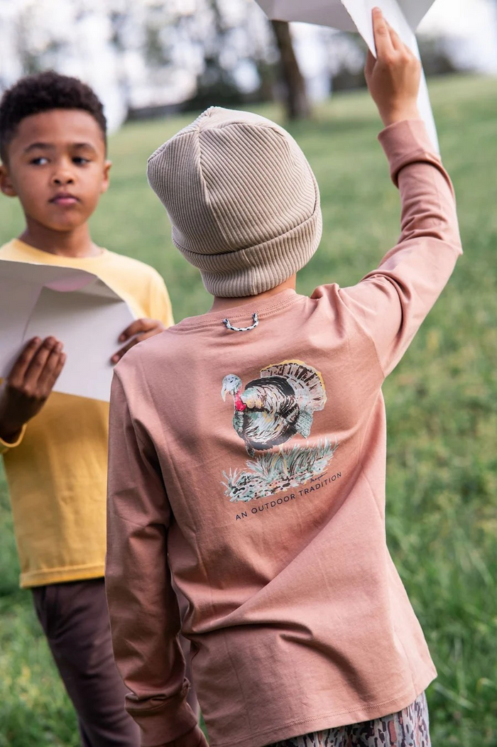 Classic long-sleeve comfort with a playful twist. This boys' tee features a turkey graphic on the back in warm burnt orange, paired with a functional front pocket for everyday wear. Soft cotton construction keeps him comfortable all day long, whether heading to school or weekend adventures. Perfect for fall layering or standalone wear.
