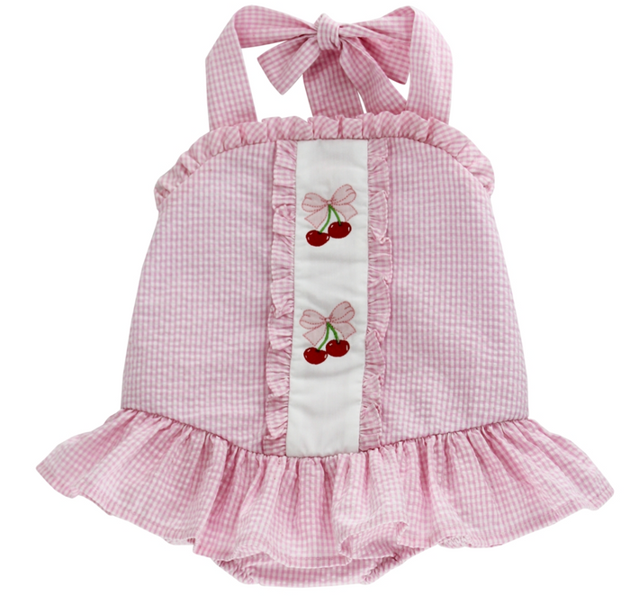 Experience the joyful spirit of summer with the Cherry Jubilee Bathing Suit by Bailey Boys! This delightful pink seersucker design, adorned with charming cherries, ensures your little one stands out at the beach or pool. The precious drop hem ruffle and halter tie neck add a touch of playful elegance, making every splash a memorable moment!