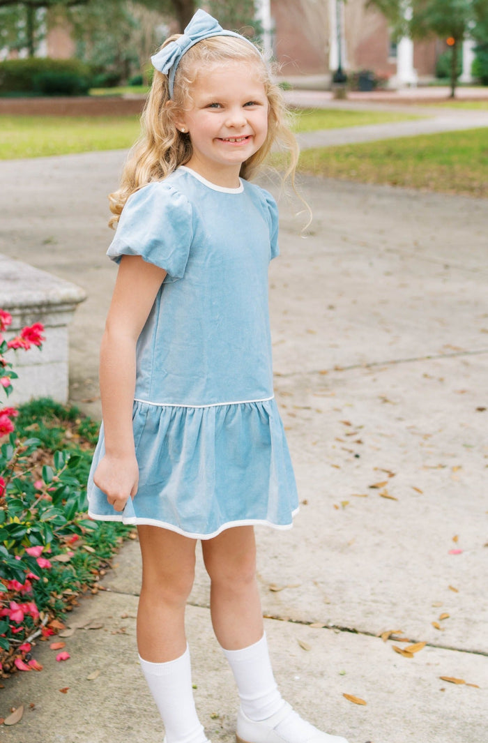 The Harper Dress captures effortless elegance in sumptuous Beaufort blue velvet. Designed for girls ages 5–8, this charming piece features an oversized back bow—a subtle yet striking detail that elevates any occasion. Whether she's attending a fall celebration or holiday gathering, the luxurious velvet drape and thoughtful silhouette make this dress a wardrobe essential. A timeless choice for special moments.