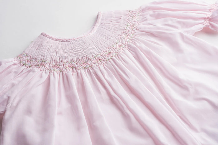 The Infant Girls Ruffle Sleeve Bishop Dress by Feltman Brothers is a delightful blend of elegance and charm. Its soft pink hue, classic smocking, and ruffle sleeves create an enchanting look, perfect for capturing precious moments. This heirloom-quality piece promises to be cherished for years to come!