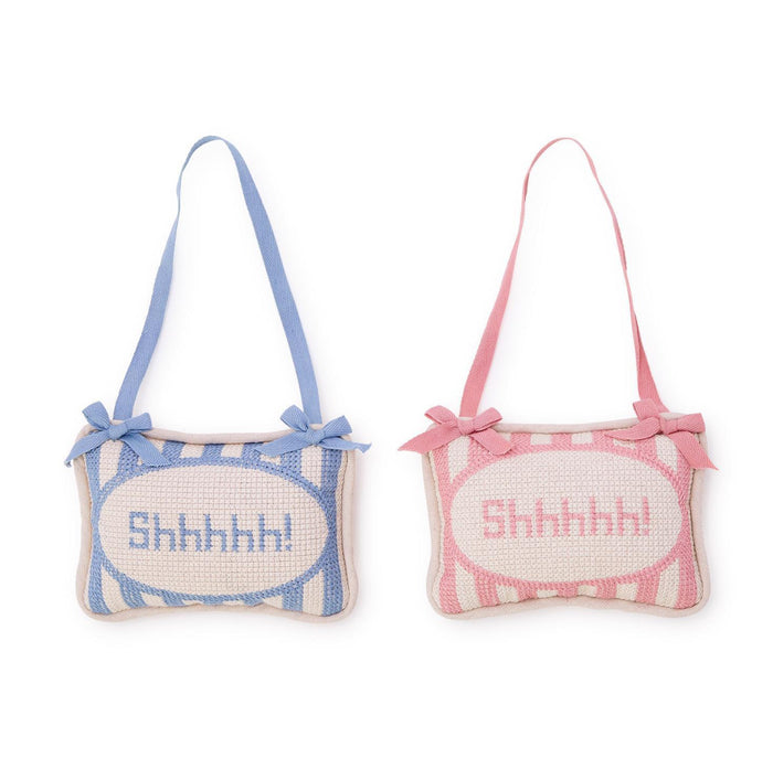 Transform your nursery into a soothing sanctuary with our Shhhhh! Embroidered Pillow Door Hanger. Made from a luxurious blend of cotton canvas, velvet, and polyester fill, this handcrafted piece adds a touch of whimsy to your little one's space. Choose from soft pink or serene blue to match your decor. Hang it on the nursery door or crib to remind guests to keep noise levels down during naptime.